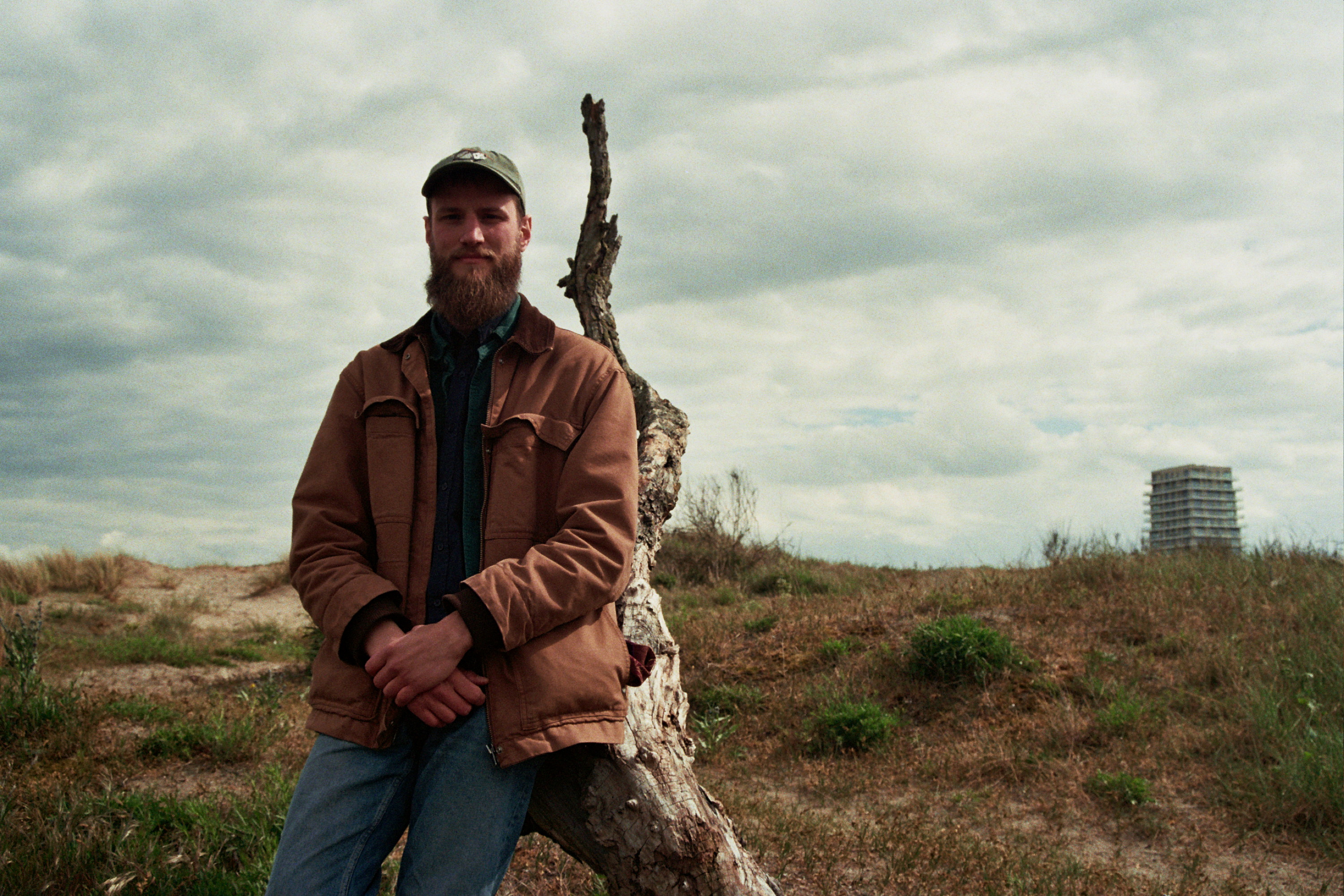 Werend Van Den Bossche in the dunes leaning against a weathered branch
